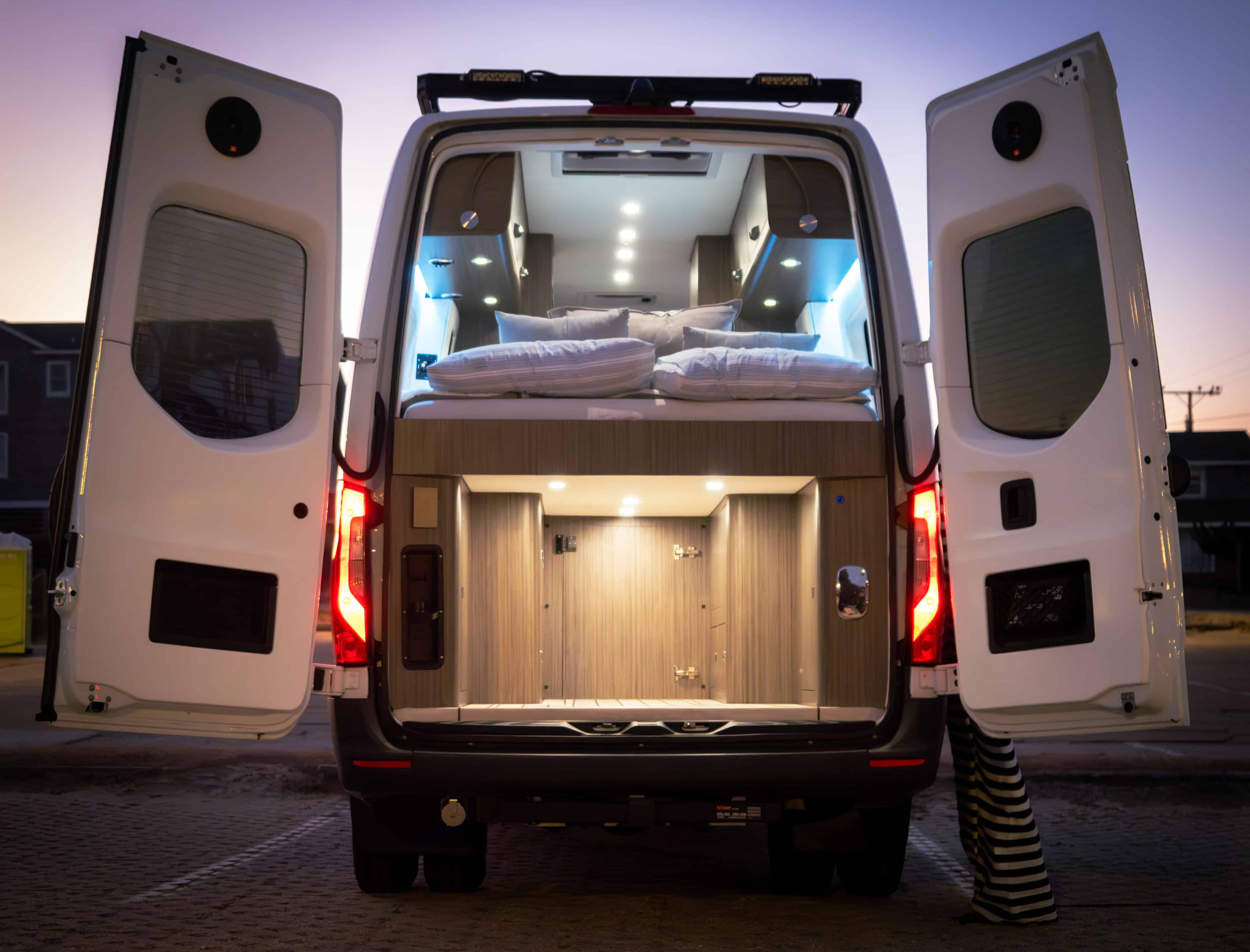 Vue arrière of fourgon aménagé with raised bed and illuminated storage compartments