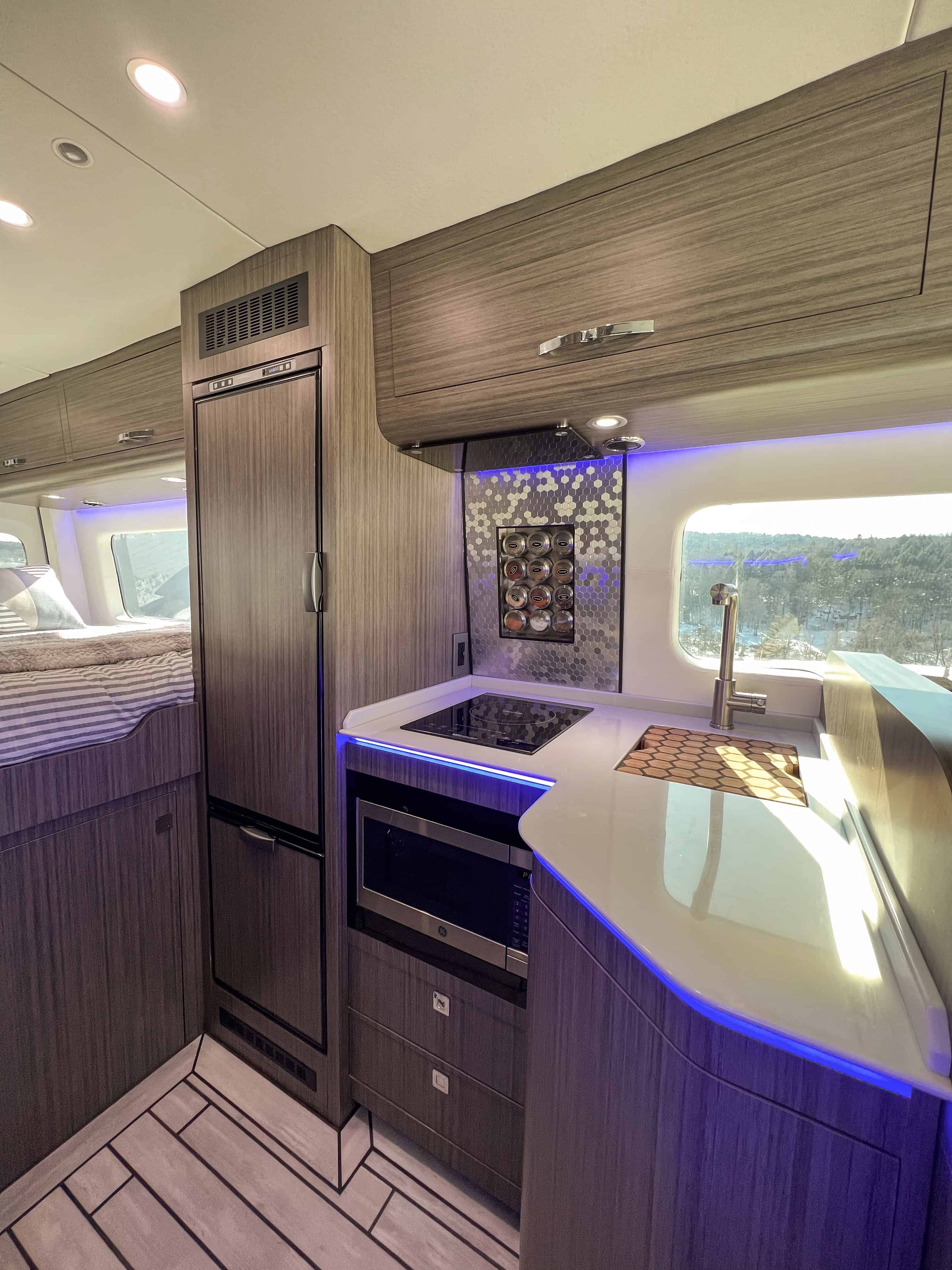 Van kitchen with induction cooktop, sink, LED lighting, and integrated armoires